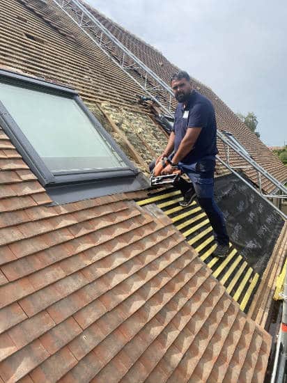Couvreur au travail sur une toiture en tuiles dans les Yvelines