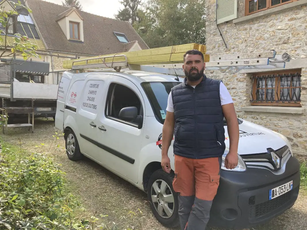 Kevin Paumard, artisan couvreur dans les Yvelines, adossé au véhicule des Toitures de Kevin